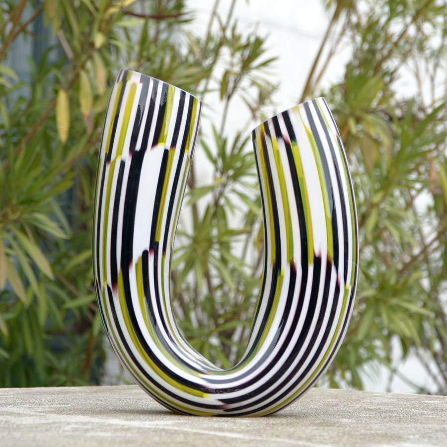 The Boomerang Twid is a unique vase designed by Marco Mencacci and realized in Murano. Mencacci can transform the material of glass into plasma, evoking the living world of the abyss, tribal rituals, the reflections of oil or latex, the transparencies of sea creatures and the pearliness of shells. 