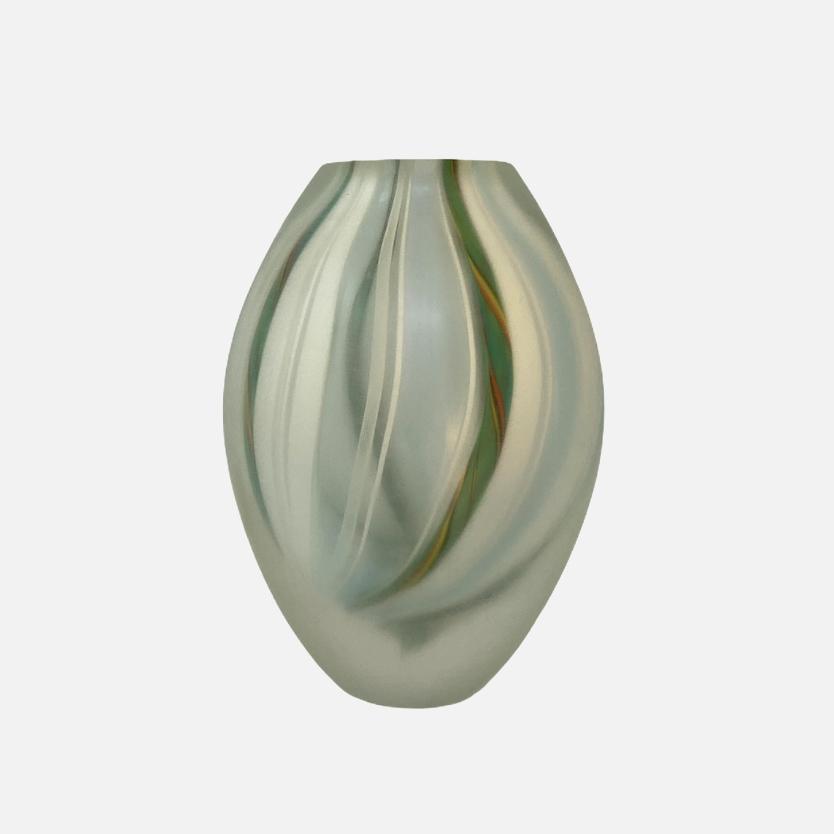 The LOVERS collection presents a selection of vases designed by Marco Mencacci and realized in Murano. Their uniqueness is rooted in the combination of transparent and filigree glass. Drawing on the century-old zanfirico process, where multiple canes are twisted as they are pulled, the threads of glass take a spiral shape that is embroidered under the surface. 